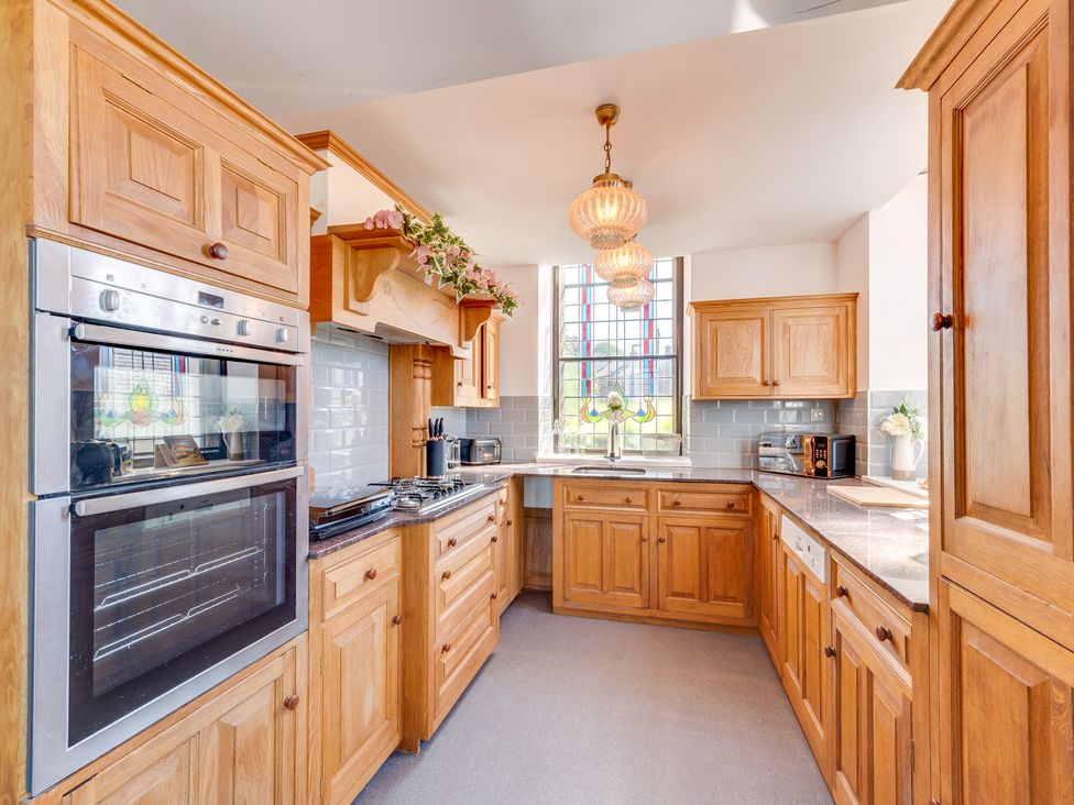 A kitchen with wooden cabinets and appliances at Birchover Chapel in Birchover