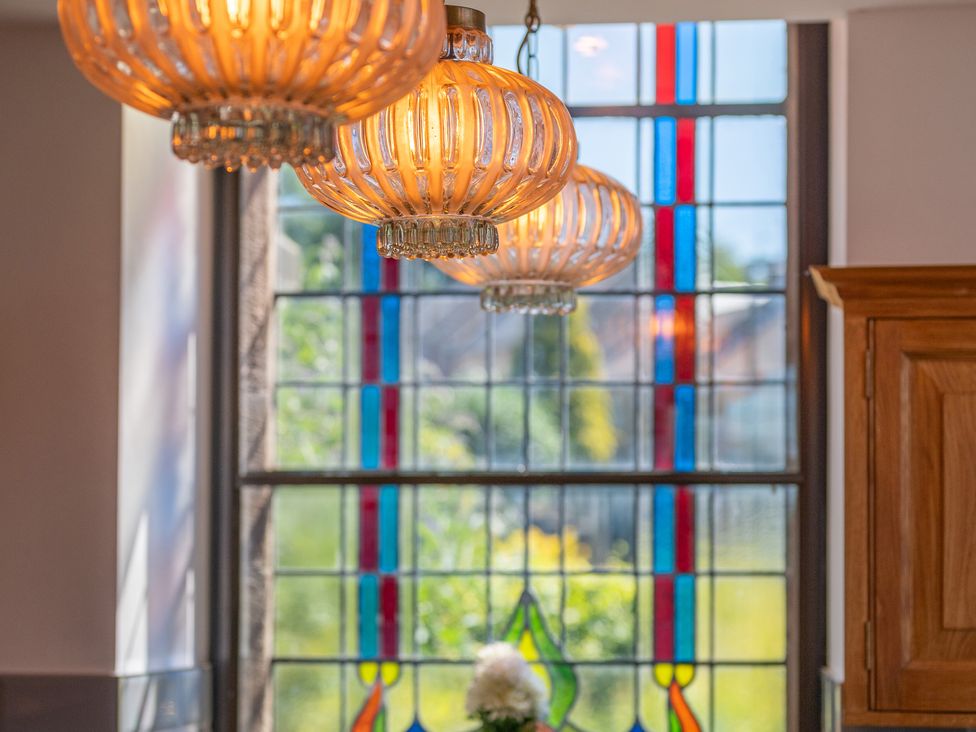 Chandeliers hanging near a stained glass window at Birchover Chapel in Birchover