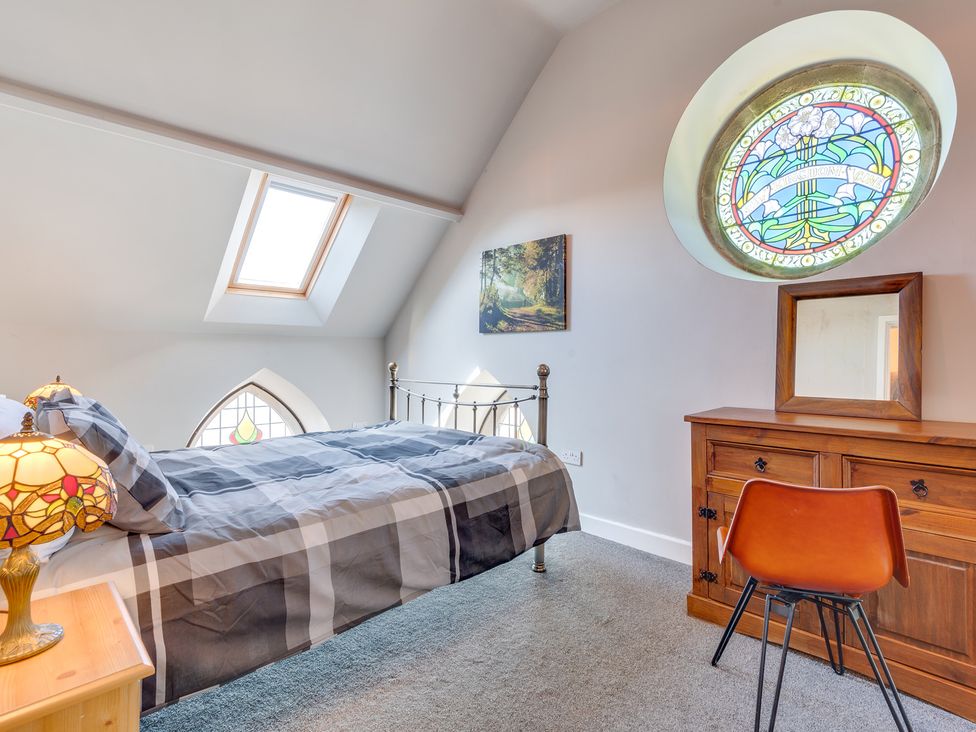 A bedroom with a bed and stained glass window at Birchover Chapel in Birchover