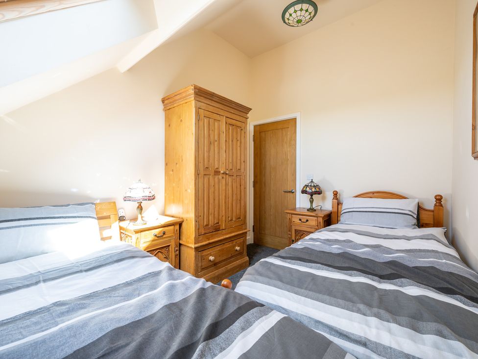 A bedroom with two beds and a wardrobe at Birchover Chapel in Birchover