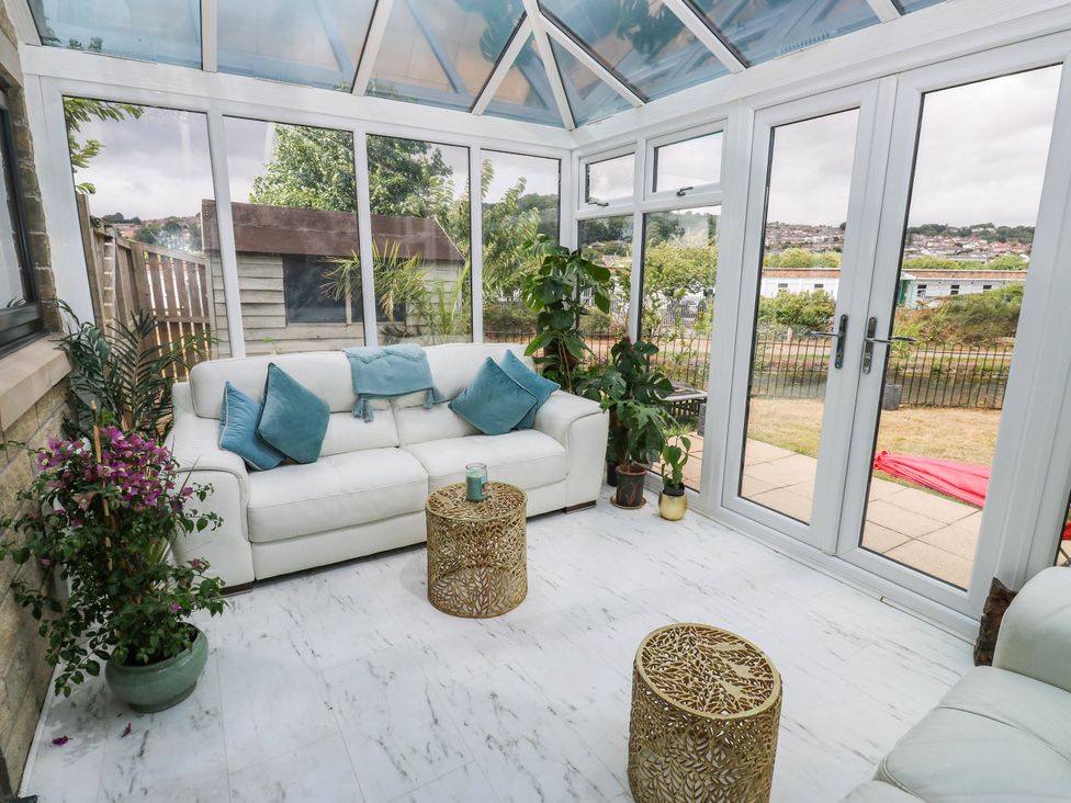 A conservatory with a sofa and plants at Canal House in Shipley