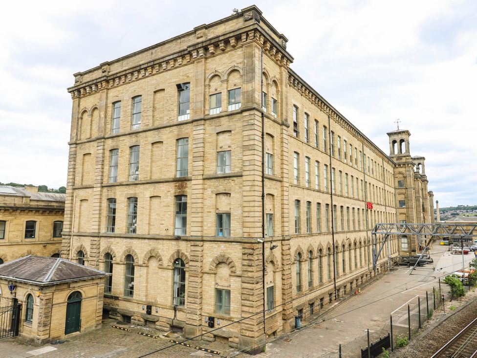 An industrial building with multiple windows and a tower at Canal House in Shipley