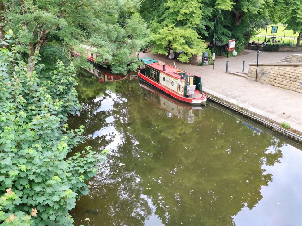 A canal with a narrowboat and trees at Canal House in Shipley