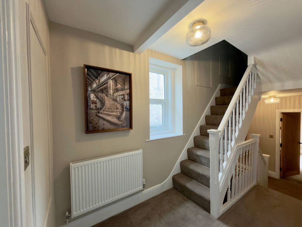 A hallway with a staircase and painting at Number 8 in Llandudno