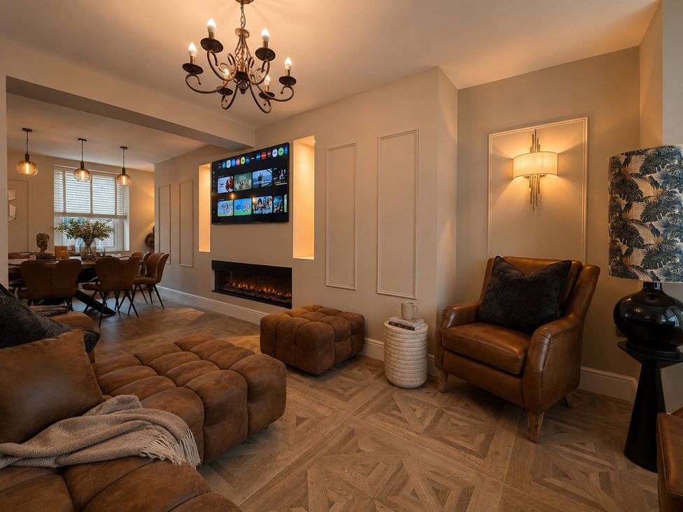 A living room with a sofa, armchair, television, and dining area at Number 8 in Llandudno