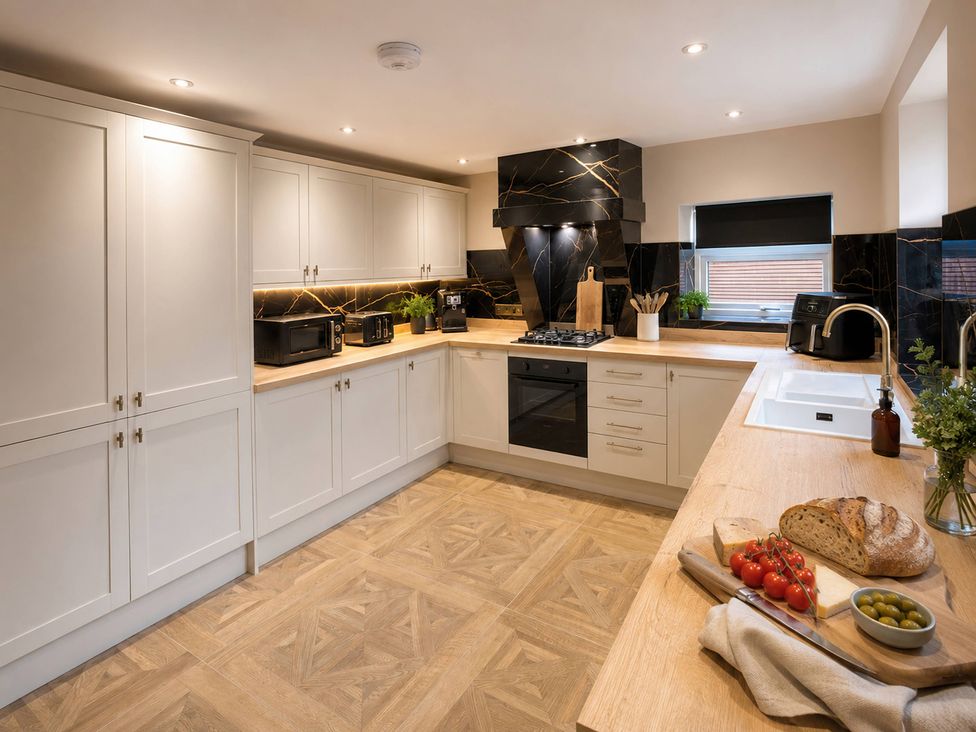 A kitchen with cabinets, counter, stove, and appliances at Number 8 in Llandudno