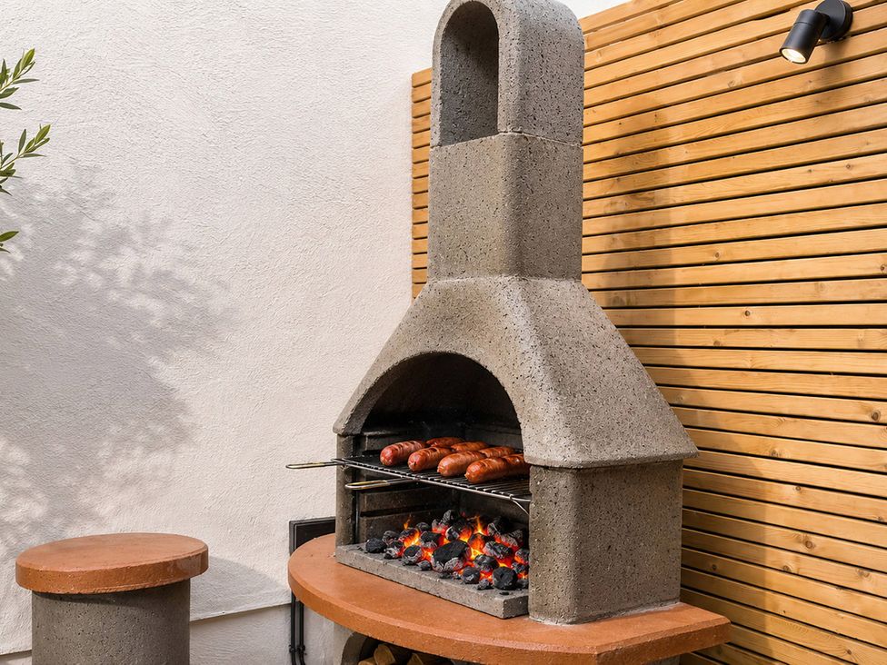 An outdoor kitchen with a barbecue grilling sausages at Number 8 Llandudno