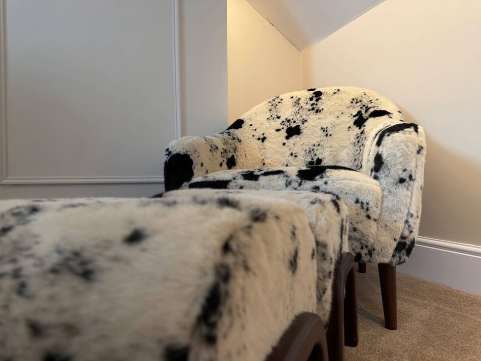 An armchair and footstool in a sitting room at Number 8 in Llandudno