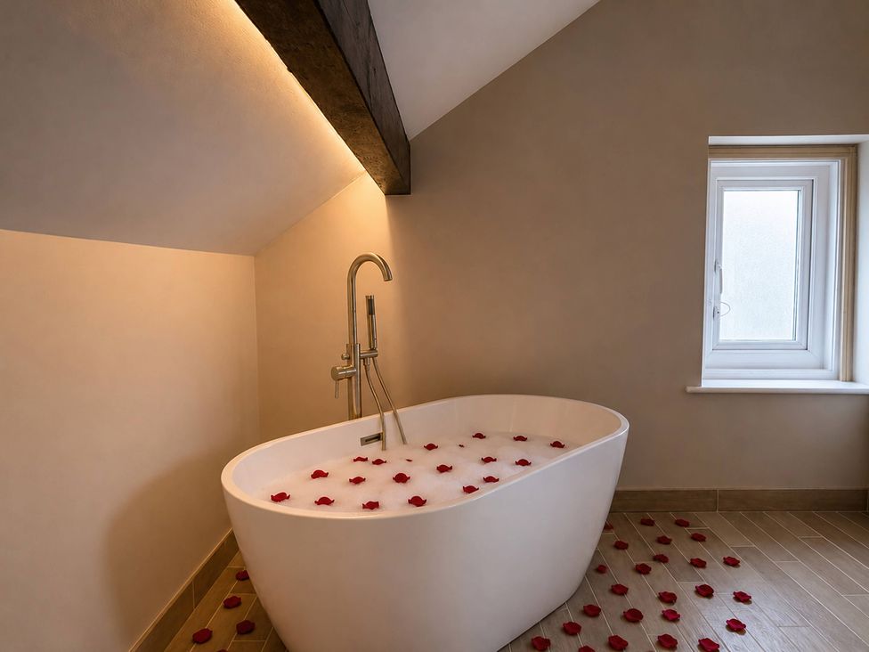 A bathroom with a bathtub and rose petals at Number 8 Llandudno