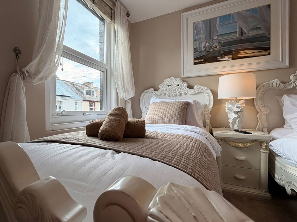 A bedroom with a bed, nightstand and a window at Number 8 Llandudno