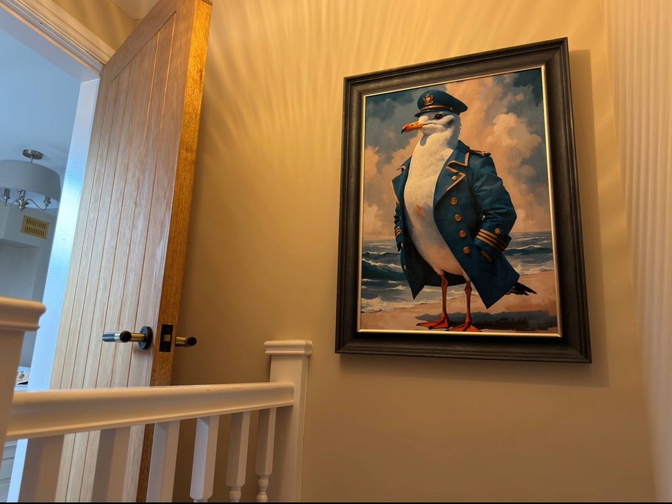 A hallway featuring a door and a painting of a seagull in a captain's coat at Number 8 Llandudno