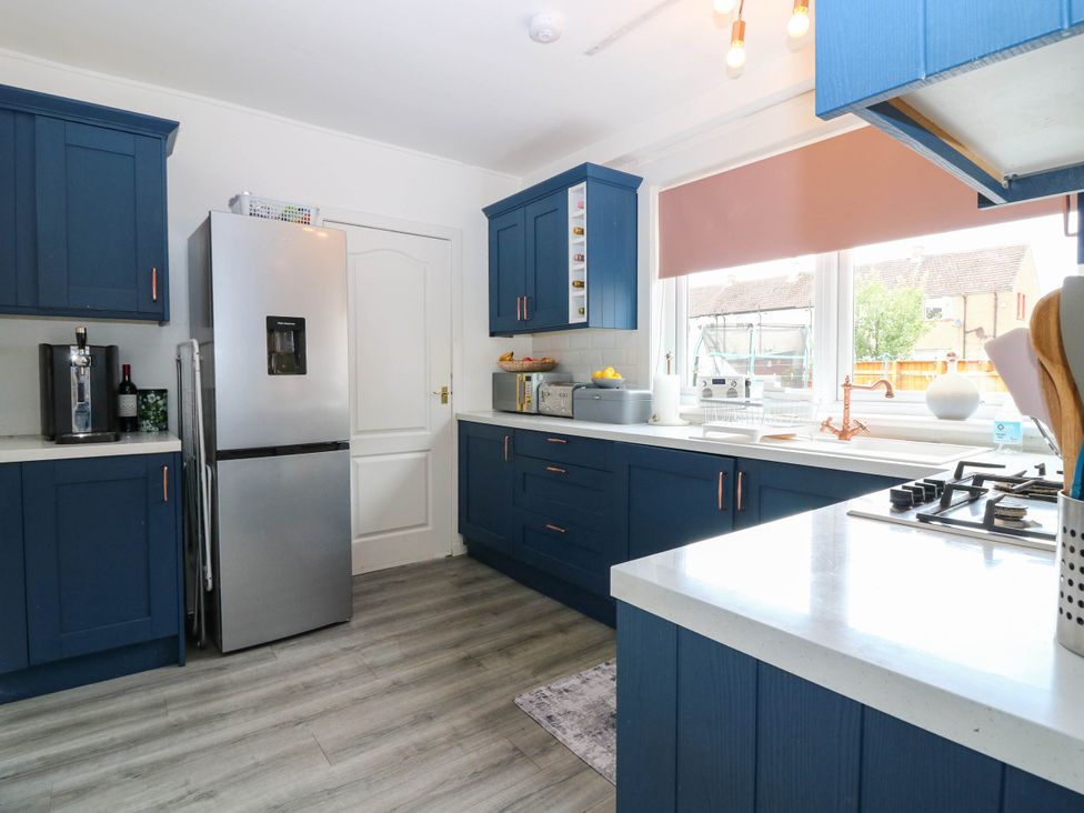 A kitchen with a refrigerator, stove, and sink at 6 Niddrie Marischal Road in Edinburgh