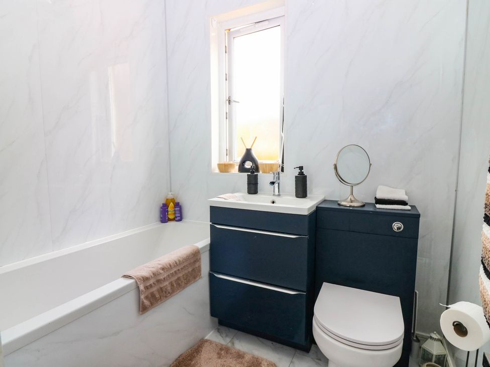 A bathroom with a bathtub, toilet, and vanity unit at 6 Niddrie Marischal Road, Edinburgh