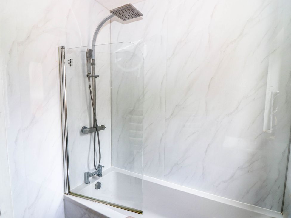 A bathtub with a shower in the bathroom at 6 Niddrie Marischal Road, Edinburgh