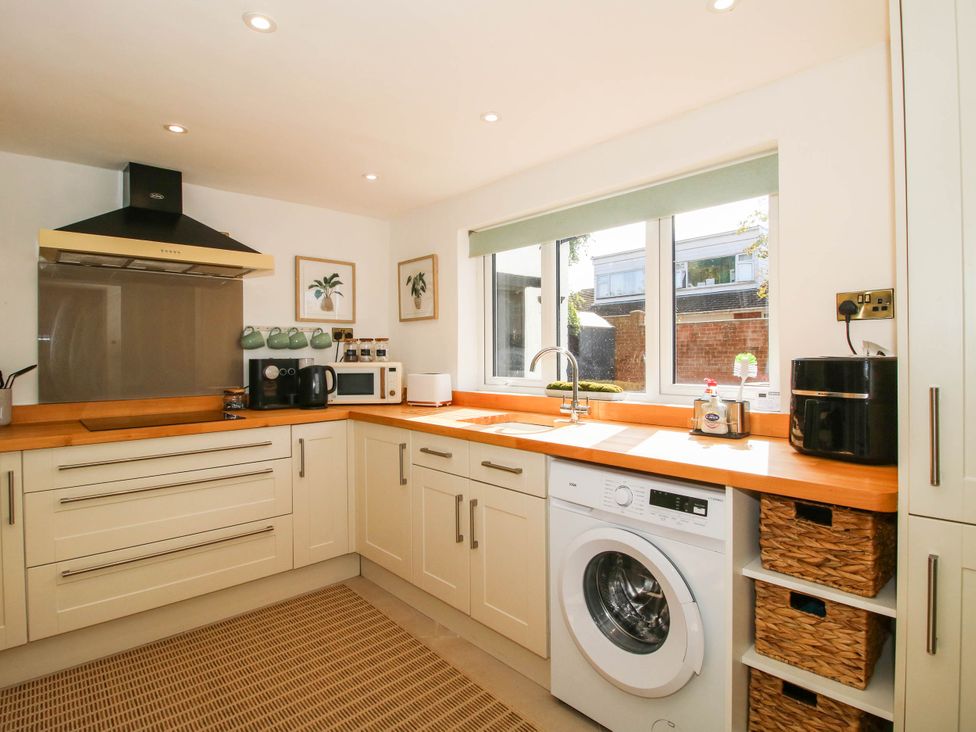 A kitchen with cabinets, sink, washing machine and microwave at The Annex at The Lodge in Shawbury