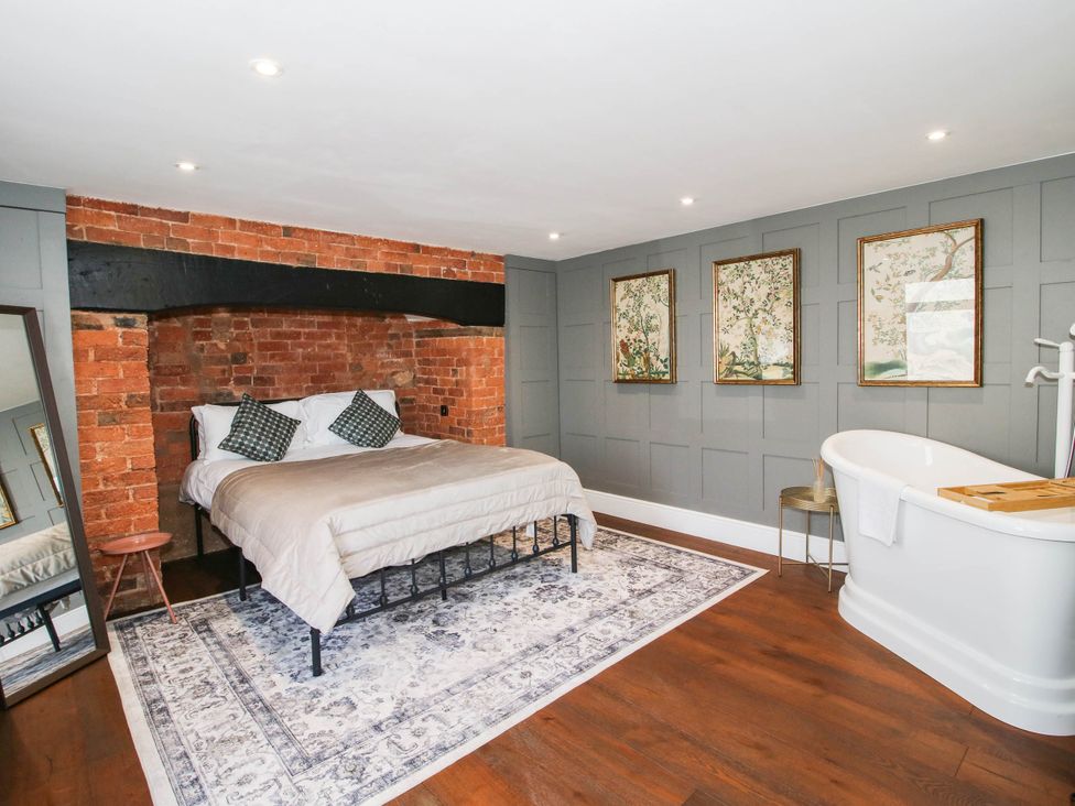 A bedroom with a bed, bathtub, and wall art at The Annex at The Lodge in Shawbury