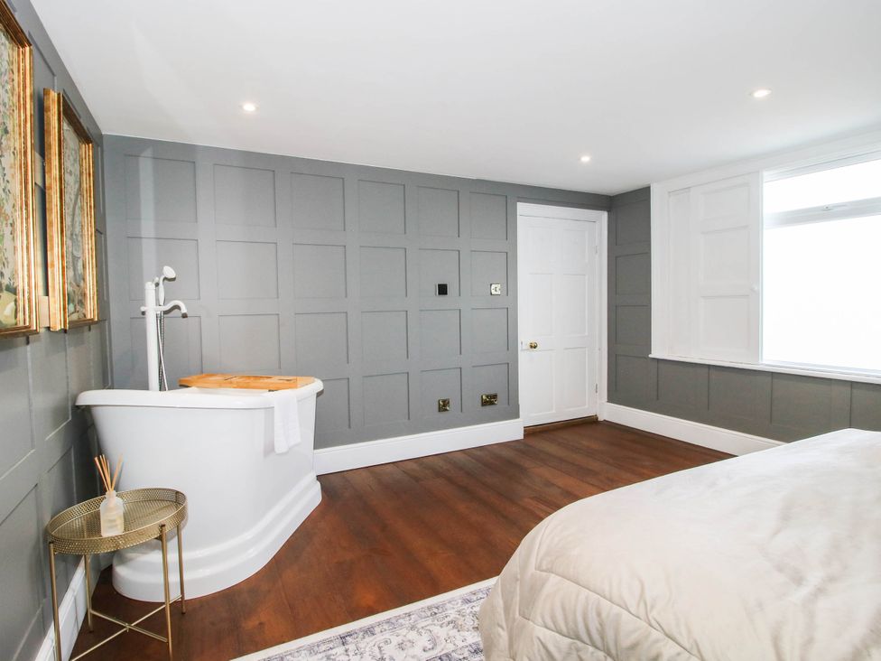 A bathroom with a bathtub and a door at The Annex at The Lodge in Shawbury