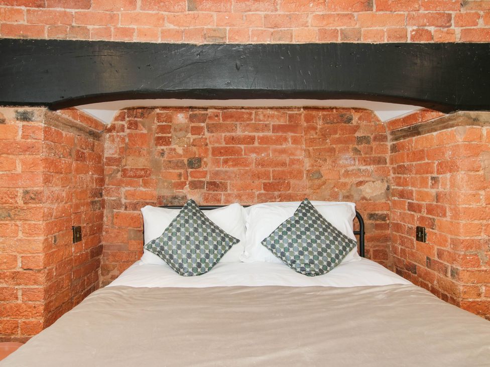 A bedroom with a bed and exposed brick wall at The Annex at The Lodge in Shawbury
