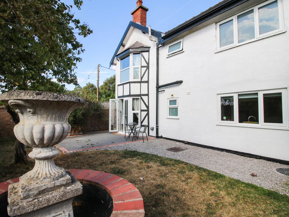 A garden with a table and chairs beside an ornamental urn at The Annex at The Lodge in Shawbury