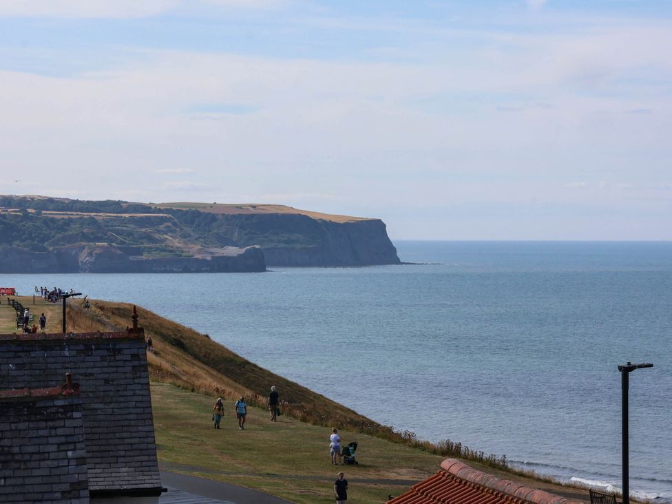 A view of the ocean and cliffs with people walking at 26 Metropole Towers in Whitby