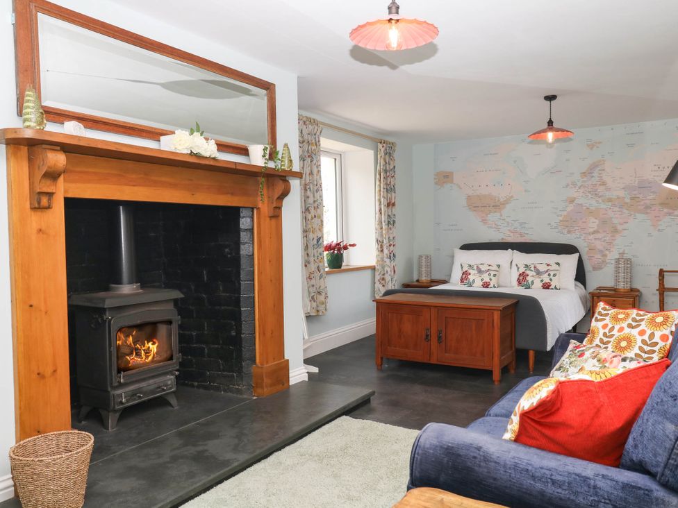 A living room with a fireplace and bed at Little Moorgate in Okehampton