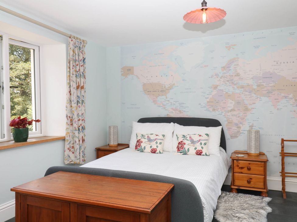 A bedroom with a bed and a world map on the wall at Little Moorgate Okehampton
