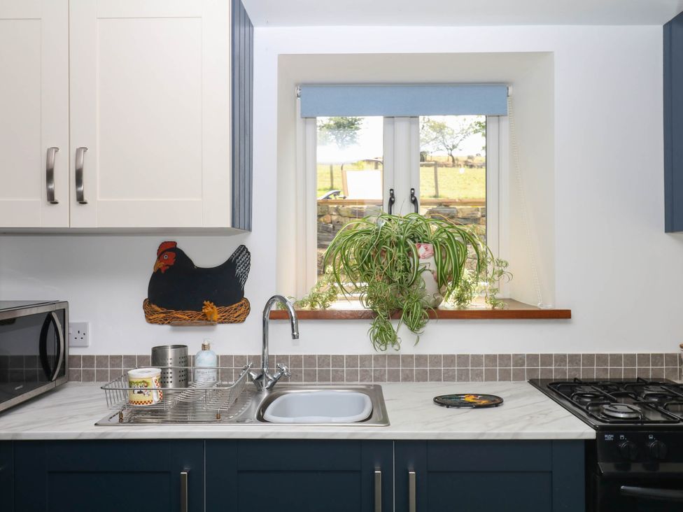 A kitchen with a sink and plants by the window at Little Moorgate in Okehampton