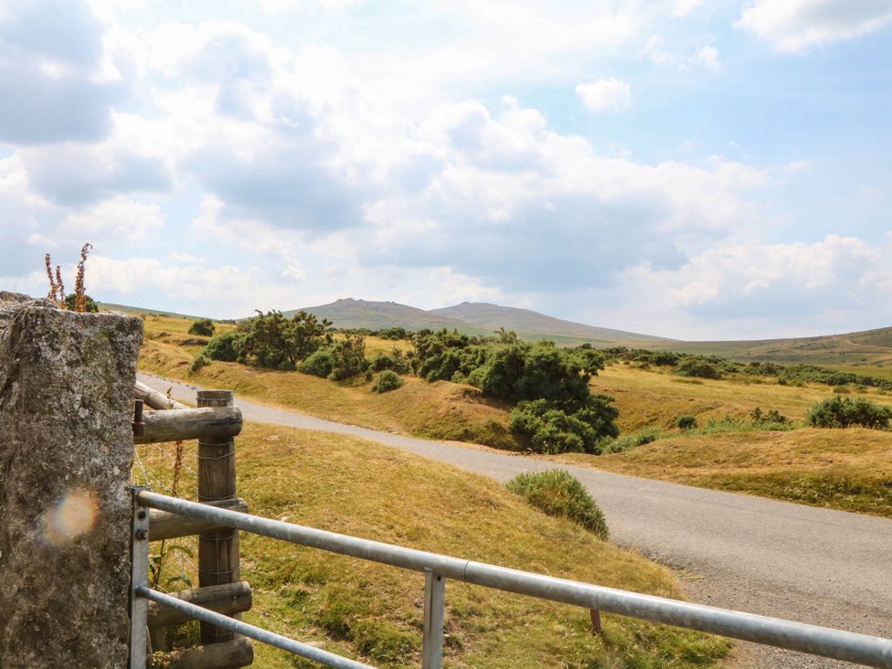 A view of a grassy landscape with a road and hills at Little Moorgate in Okehampton