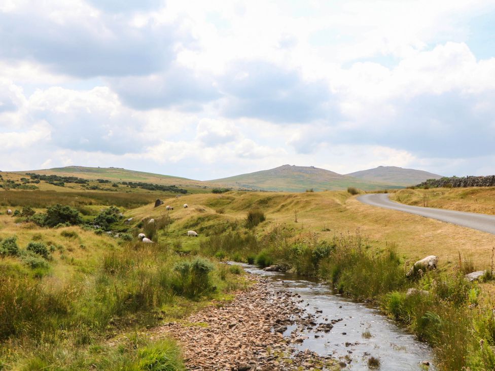 A landscape with a stream and road surrounded by hills at Little Moorgate in Okehampton