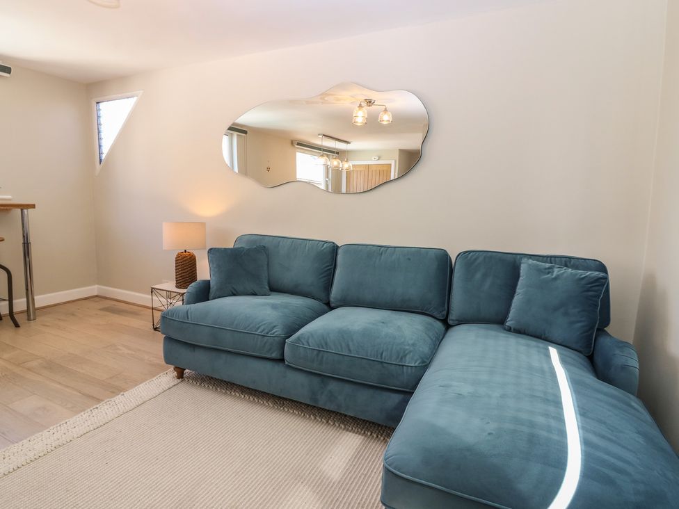 A living room with a sofa and a mirror at The Herring's Lean in Eyemouth