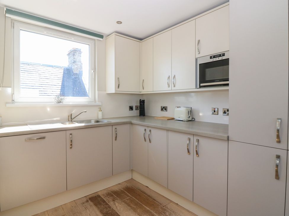 A kitchen with cabinets and a window at The Herring's Lean in Eyemouth