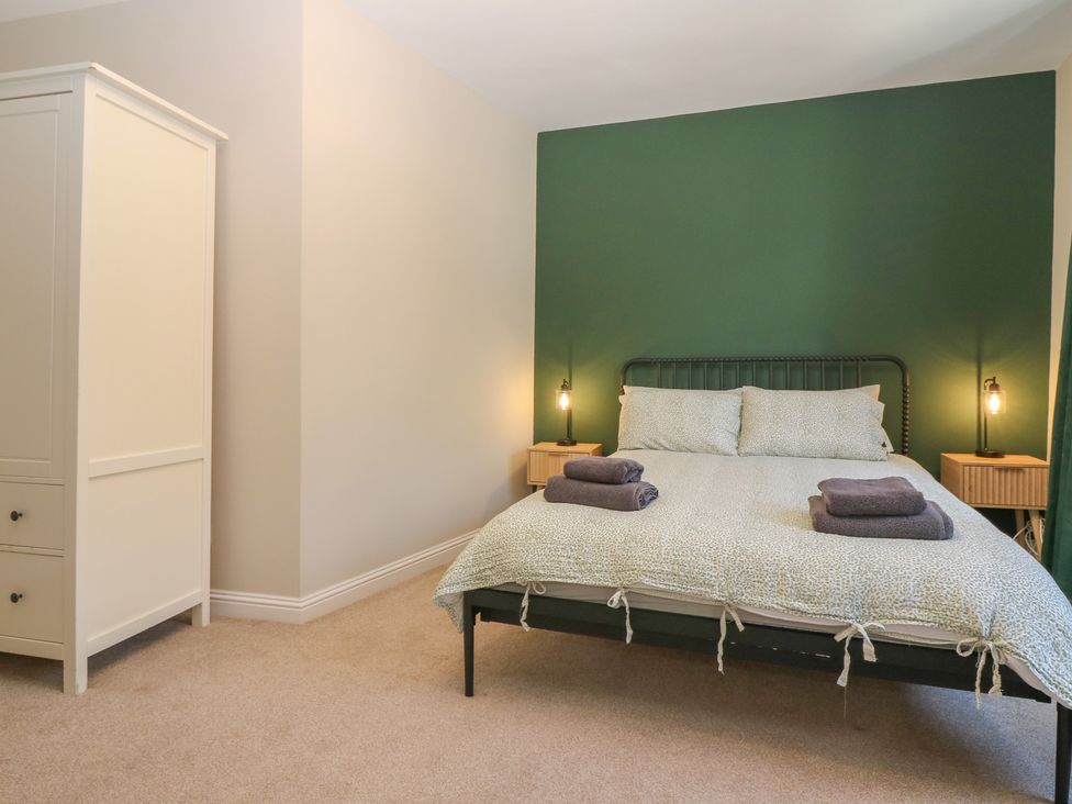 A bedroom with a bed, wardrobe and nightstands at The Herring's Lean in Eyemouth