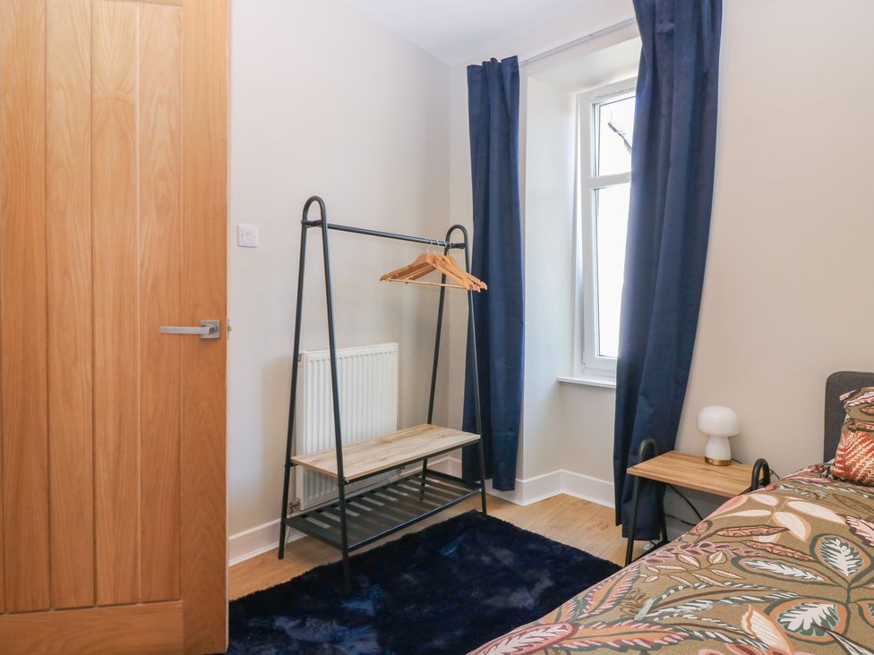A bedroom with a clothing rack and a nightstand at The Herring's Lean in Eyemouth
