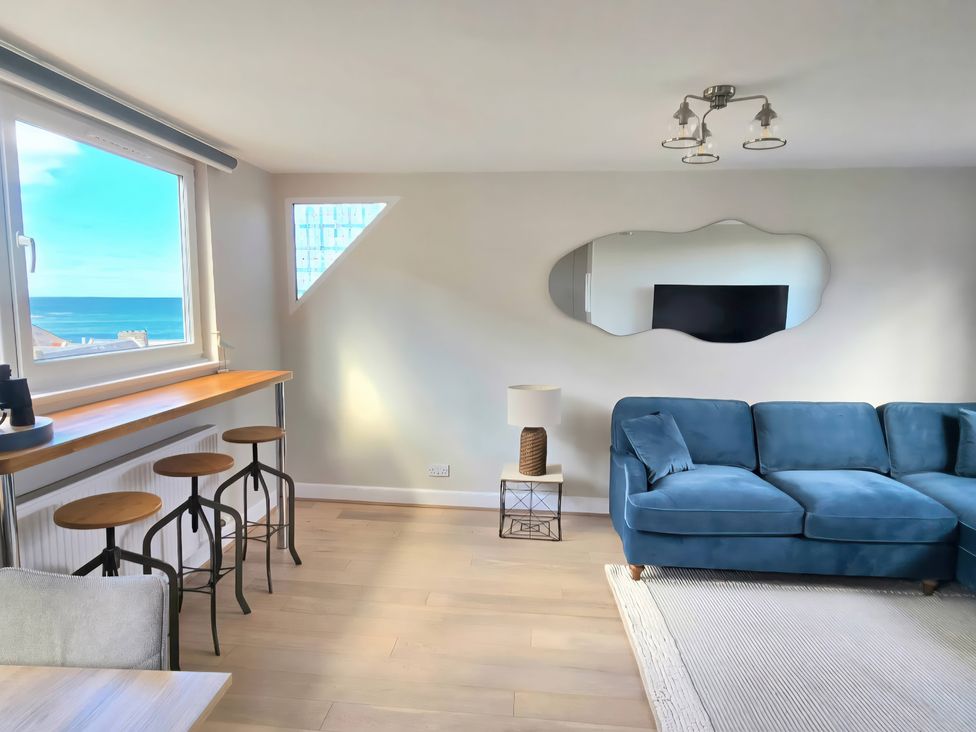 A living room with a sofa and a window view at The Herring's Lean in Eyemouth