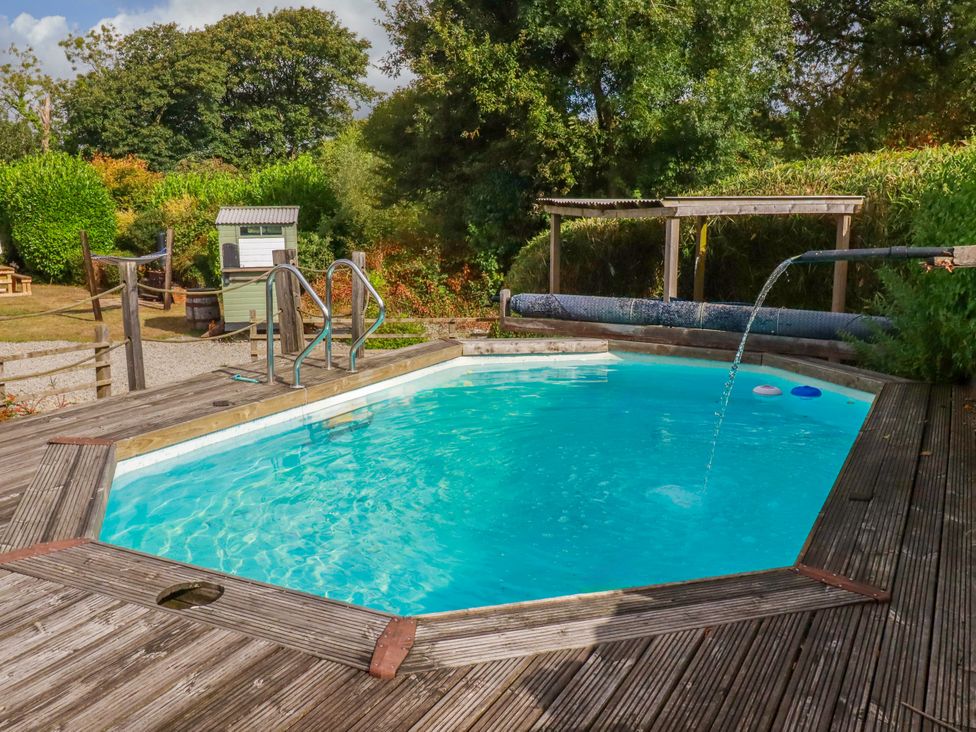A swimming pool with a fountain and steps at Honey Bee Cottage in Menheniot