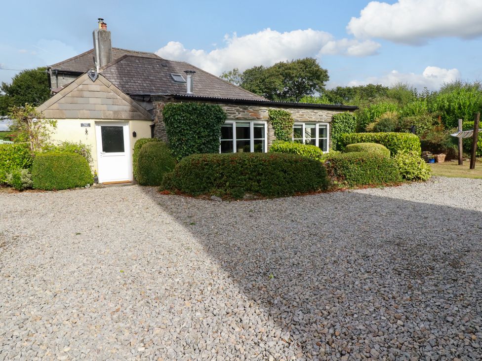 A house with gravel driveway and bushes at Honey Bee Cottage in Menheniot