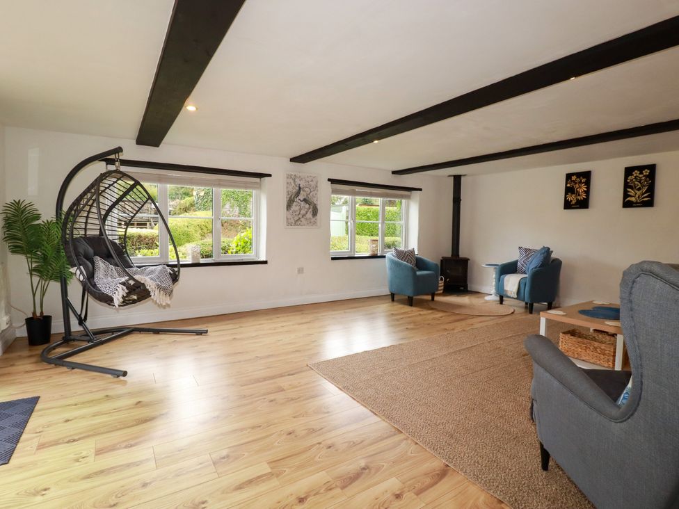 A living room with a hanging chair and seating area at Honey Bee Cottage in Menheniot