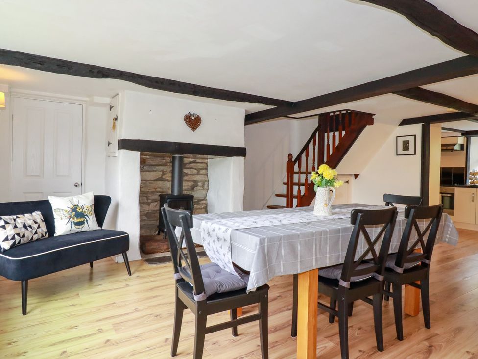 A dining room with a table and chairs at Honey Bee Cottage in Menheniot