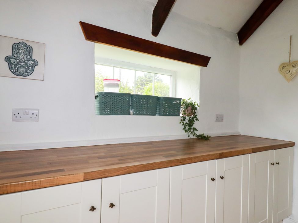 A kitchen with countertop and storage baskets at Honey Bee Cottage in Menheniot