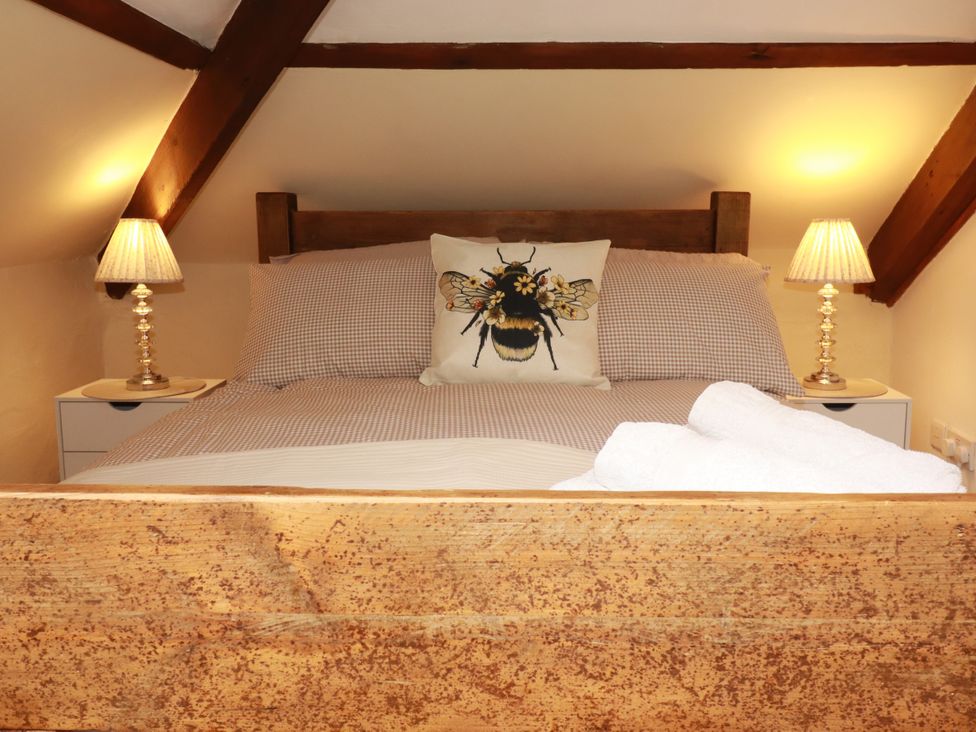 A bedroom with a bed and two bedside lamps at Honey Bee Cottage in Menheniot