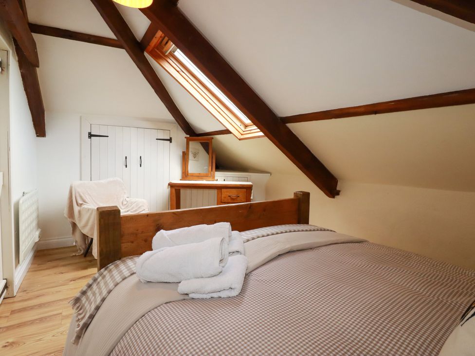 A bedroom with a bed and window at Honey Bee Cottage Menheniot