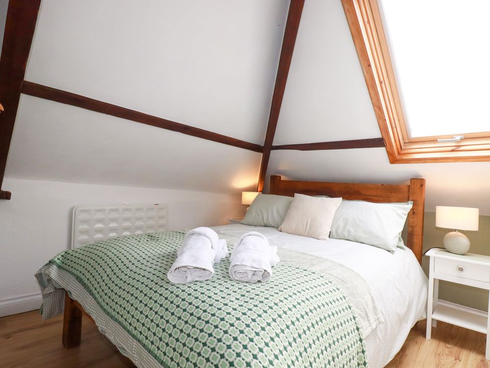 A bedroom with a bed and nightstand at Honey Bee Cottage in Menheniot