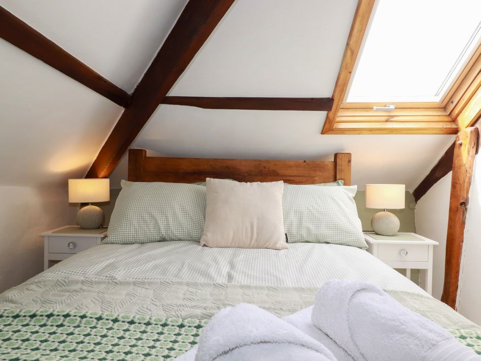 A bedroom with a bed and lamp at Honey Bee Cottage in Menheniot