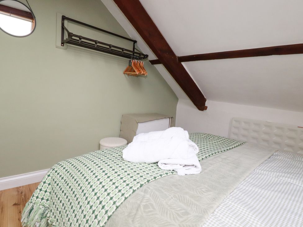 A bedroom with a bed and hangers at Honey Bee Cottage Menheniot