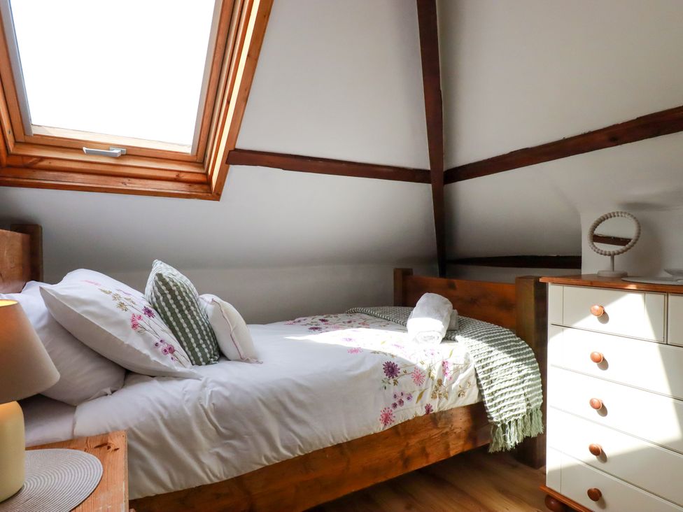 A bedroom with a bed and dresser at Honey Bee Cottage in Menheniot