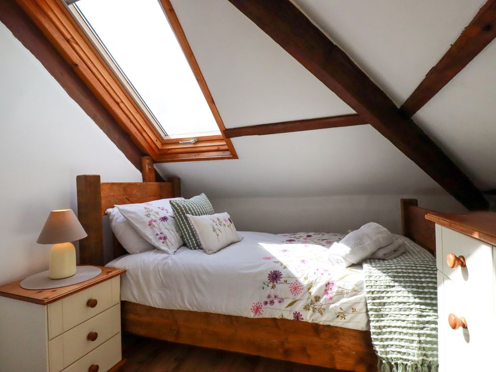 A bedroom with a bed and a lamp at Honey Bee Cottage in Menheniot