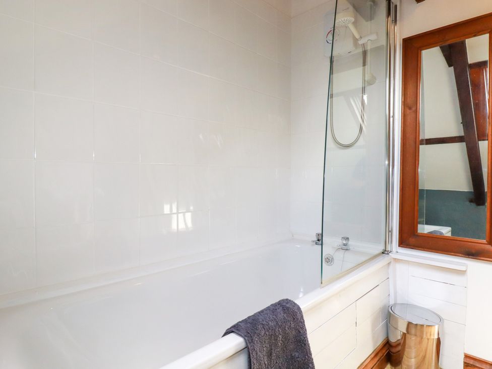 A bathroom with a bathtub and shower at Honey Bee Cottage in Menheniot