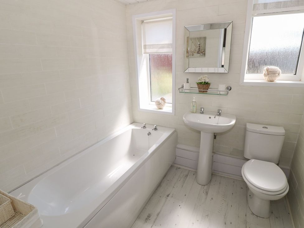 A bathroom with a bathtub, sink, and toilet at Beachway, Holywell