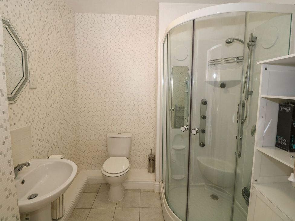 A bathroom with a shower, toilet, sink, and mirror at Beachway in Holywell