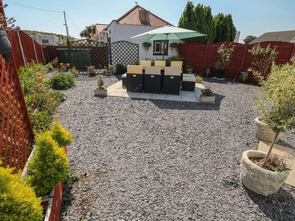 A garden with a patio table and chairs under an umbrella at Beachway in Holywell